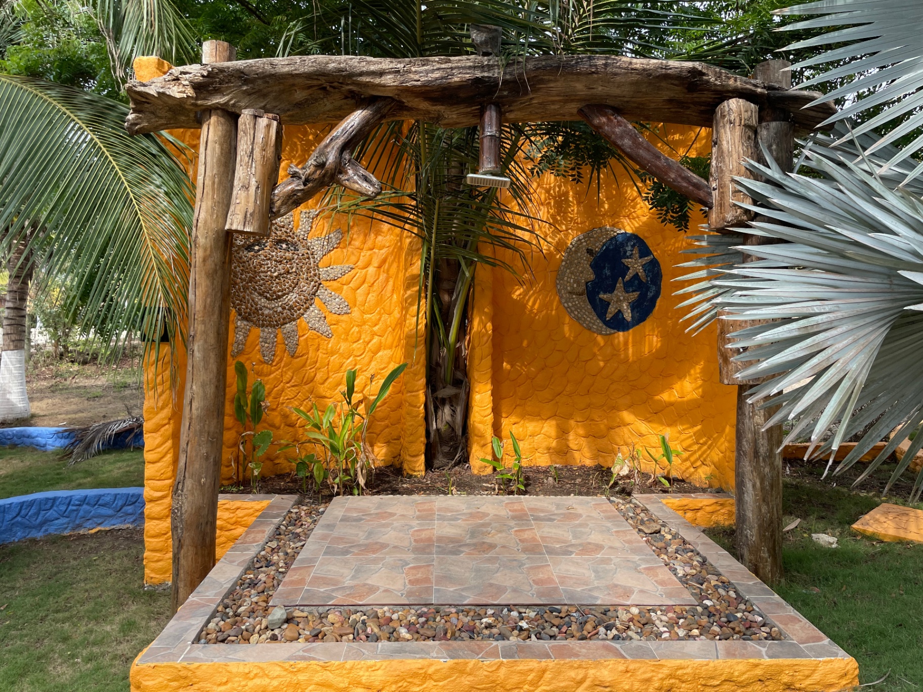 Mural artesanal de sol y luna en el jardín tropical