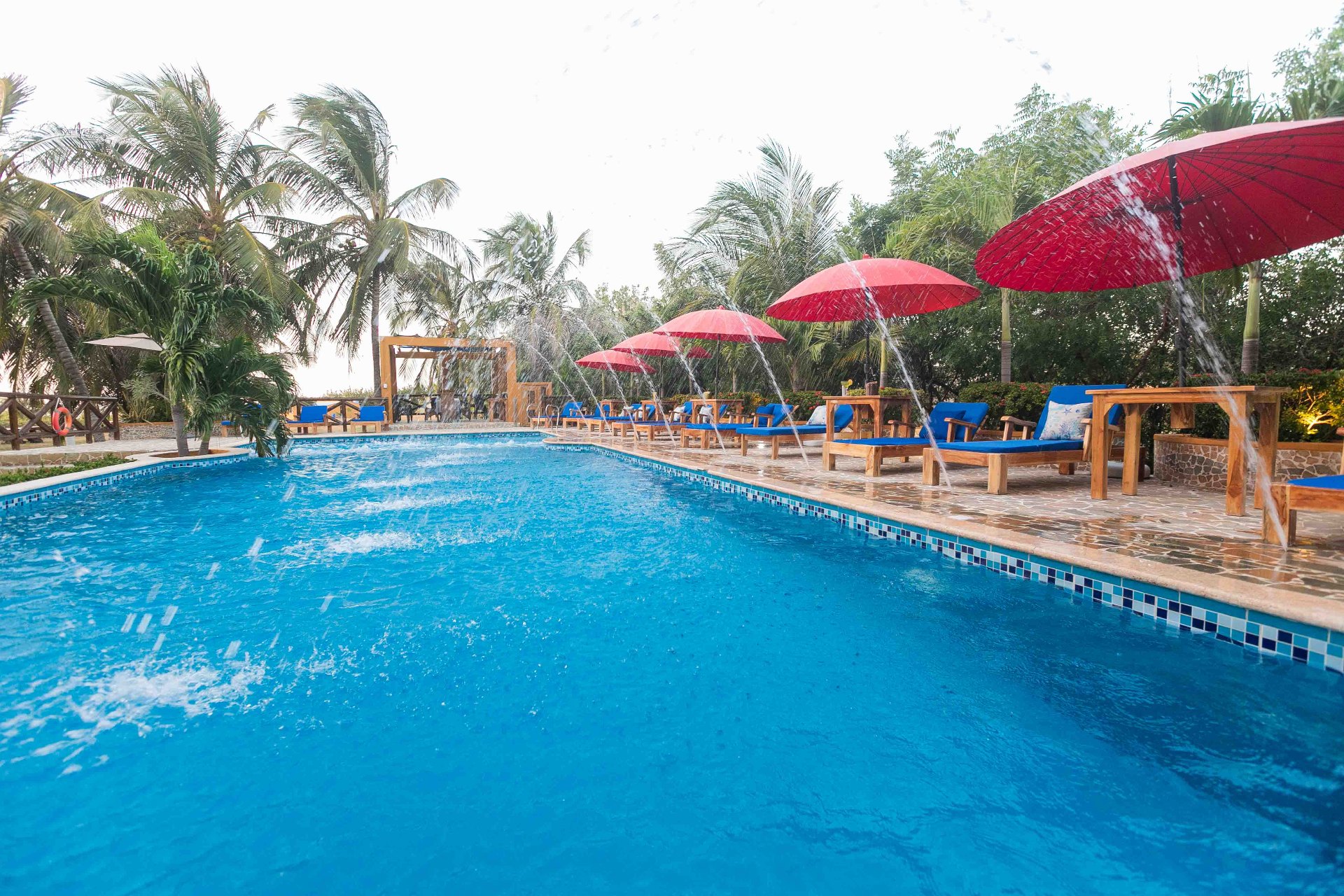 Piscina con sombrillas rojas y fuentes de agua