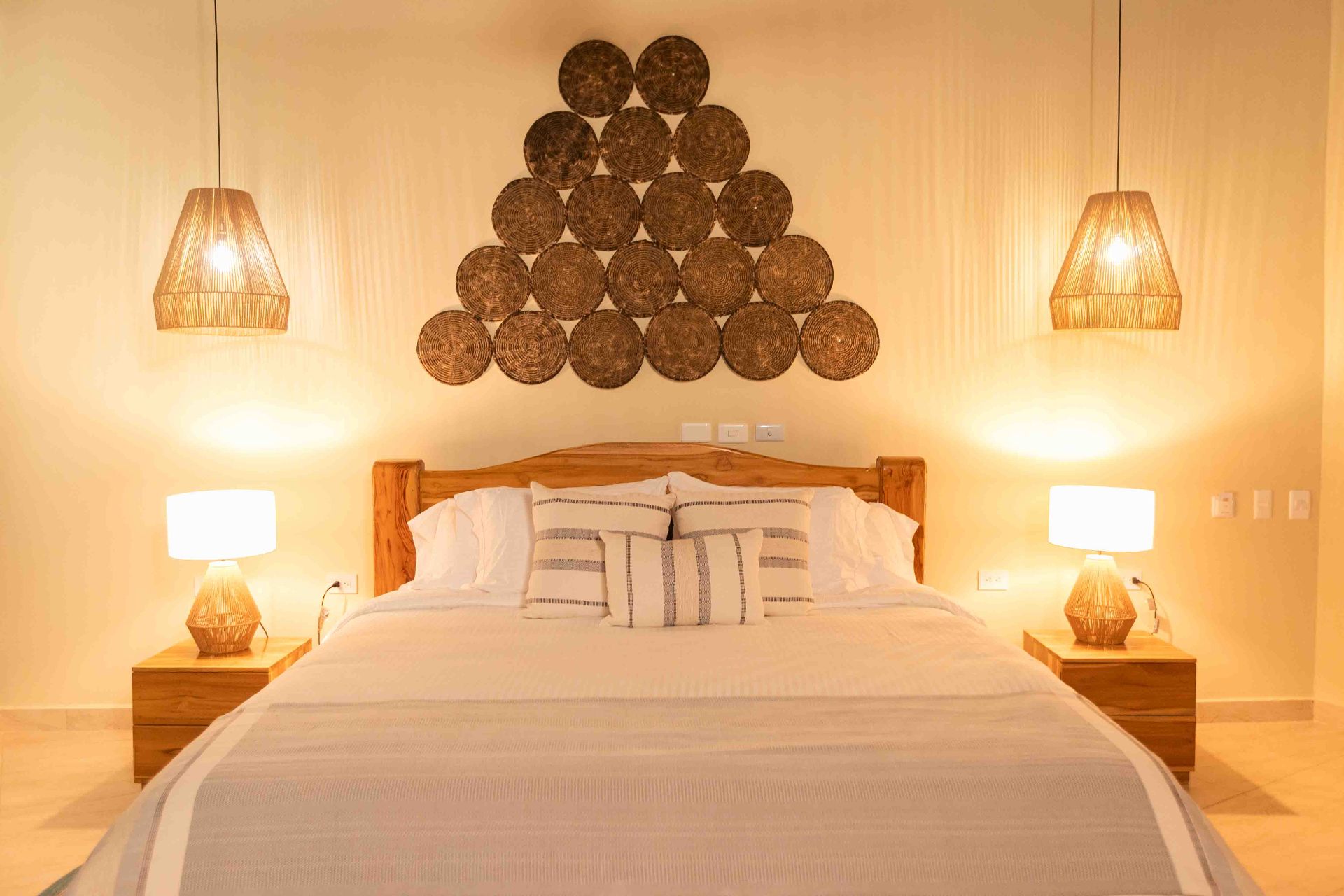 King bed with artisan pendant lamps at Marahuaco Beach House boutique hotel Colombia